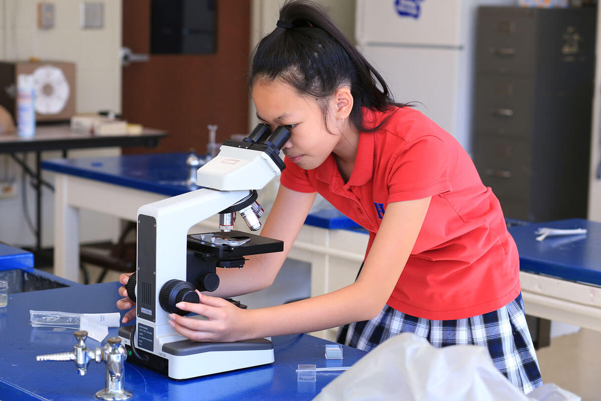 a girl looking through a microscope